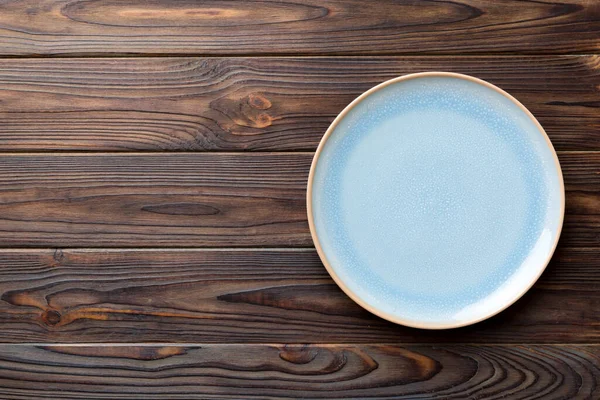 Ahşap zemindeki boş mavi tabağın üst görüntüsü. Tasarımın için boş boşluk.