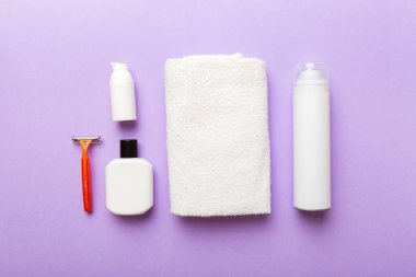 Tıraş Adam seti. Traş makinesi, havlu, losyon ve renkli arka planda tıraş köpüğü. Erkekler banyo aksesuarları üst görünüm.