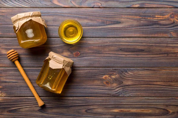 Honey jar with wooden honey dipper on white background top view with copy space. Delicious honey bottle.