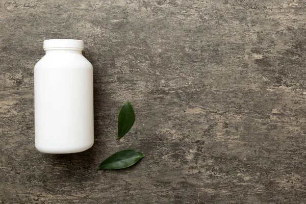 supplement pills with medicine bottle health care and medical top view. Vitamin tablets. Top view mockup bottle for pills and vitamins with green leaves, natural organic bio supplement, copy space.
