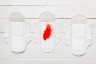 Kadın hijyen ürünleri ya da arka planda kırmızı tüy olan hijyenik ped. Pastel renk. - Yakın çekim. Mesaj için boş bir yer. Kadın günlük hijyeni..