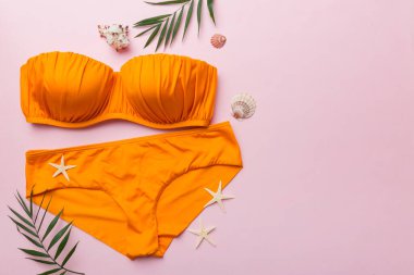 Kadın mayo ve plaj aksesuarları renkli arka plan yaz seyahati konseptine düz bir görünüm kazandırıyordu. Bikini mayo, hasır şapka ve deniz topuklu ayakkabı. Üst görünümü kopyala.