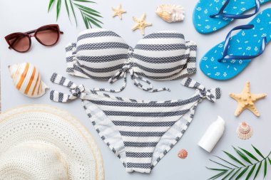 Kadın mayo ve plaj aksesuarları renkli arka plan yaz seyahati konseptine düz bir görünüm kazandırıyordu. Bikini mayo, hasır şapka ve deniz topuklu ayakkabı. Üst görünümü kopyala.