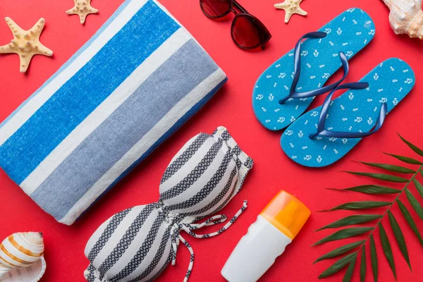 Kadın mayo ve plaj aksesuarları renkli arka plan yaz seyahati konseptine düz bir görünüm kazandırıyordu. Bikini mayo, hasır şapka ve deniz topuklu ayakkabı. Üst görünümü kopyala.