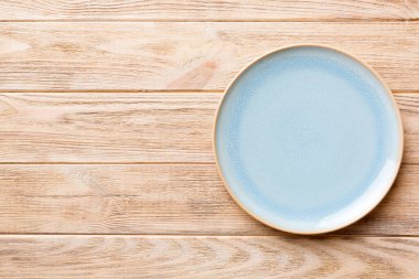 Ahşap zemindeki boş mavi tabağın üst görüntüsü. Tasarımın için boş boşluk.