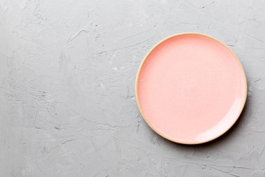 Çimento arka planındaki boş pembe tabağın üst görüntüsü. Tasarımın için boş boşluk.