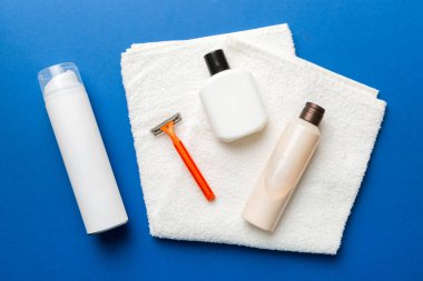 Tıraş Adam seti. Traş makinesi, havlu, losyon ve renkli arka planda tıraş köpüğü. Erkekler banyo aksesuarları üst görünüm.