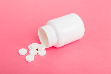 İlaç şişesinden alınan farklı uyuşturucu ve sağlık takviyesi hapları ve renkli arka plana ilişkin tıbbi genel görünüm.