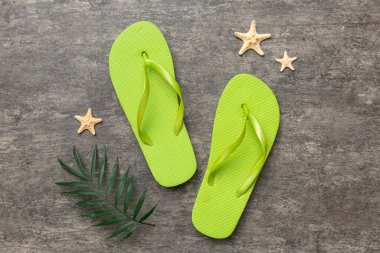 Renkli arka planda parmak arası terlikleri ve deniz kabuğu olan düz bir kompozisyon. Metin üstü görünümü için boşluk.