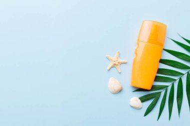 Güneş kremi şişesi. Güneş korumalı krem ve tropik yeşil yapraklı deniz kabukları olan bir şişe..