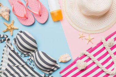 Kadın mayo ve plaj aksesuarları renkli arka plan yaz seyahati konseptine düz bir görünüm kazandırıyordu. Bikini mayo, hasır şapka ve deniz topuklu ayakkabı. Üst görünümü kopyala.