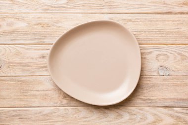 Ahşap arka planda boş pembe tabağın üst görüntüsü. Tasarımın için boş boşluk.