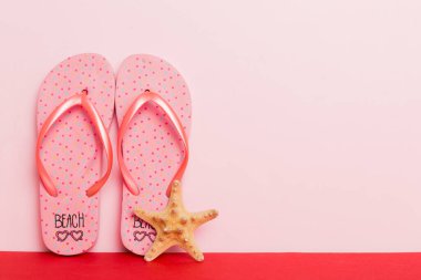 Plaj aksesuarları. Renkli arka planda parmak arası terlik ve denizyıldızı. Kopyalama alanı kullan.