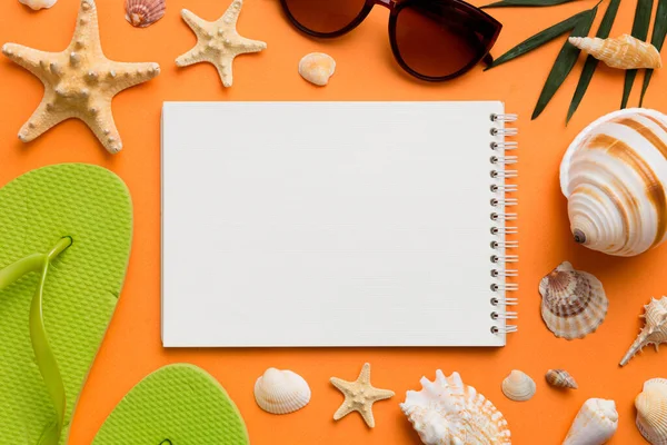 Blank writing book with summer beach accessories on background, copy space. Flat lay with copy space.