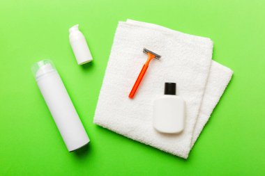 Tıraş Adam seti. Traş makinesi, havlu, losyon ve renkli arka planda tıraş köpüğü. Erkekler banyo aksesuarları üst görünüm.