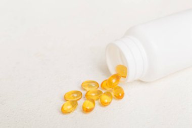 Omega-3 kapsülleri masa arkasında beyaz bir şişede yatıyor. Balık yağı tabletlerinin üst görüntüsü. Biyolojik olarak aktif katkı maddeleri. omega 6, omega 9, A vitamini, D vitamini, D3 vitamini, akşam çuha çiçeği yağı.