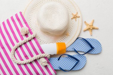 Plaj aksesuarları renkli arka plan yaz seyahati konseptinde düz bir görünüm sergiliyordu. İçinde deniz yıldızı ve deniz kabuğu olan bir çanta. Üst görünüm.