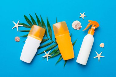 Güneş kremi şişesi. Güneş korumalı krem ve tropik yeşil yapraklı deniz kabukları olan bir şişe..