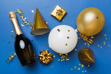 Renkli arka planda şampanya şişesi hediye paketi kurdeleleri ve konfetilerin düz kompozisyonu vardı. Düz konum, üst görünüm tatil konsepti.