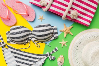 Kadın mayo ve plaj aksesuarları renkli arka plan yaz seyahati konseptine düz bir görünüm kazandırıyordu. Bikini mayo, hasır şapka ve deniz topuklu ayakkabı. Üst görünümü kopyala.