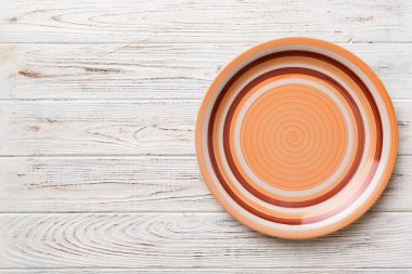 Ahşap arka planda boş turuncu tabağın üst görüntüsü. Tasarımın için boş boşluk.