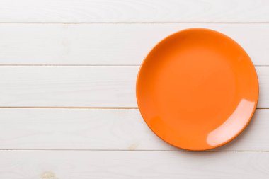 Ahşap arka planda boş turuncu tabağın üst görüntüsü. Tasarımın için boş boşluk.