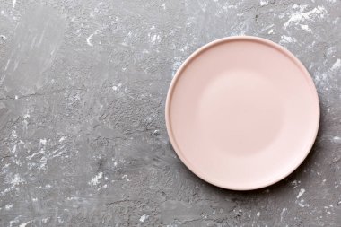 Çimento arka planındaki boş pembe tabağın üst görüntüsü. Tasarımın için boş boşluk.