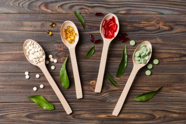 Renkli arka planda tahta kaşıkta vitamin ve mineral haplarının üst görünümü. Muhtelif ilaç haplarının en üst görüntüsü. Beslenme takviyesi sağlık ürünleri.