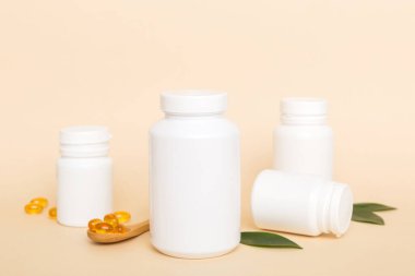 Omega-3 kapsülleri yeşil yapraklı arka planda beyaz bir şişede yatar. Balık yağı tabletleri. Biyolojik olarak aktif katkı maddeleri. Omega 6, Omega 9, A vitamini, E, D vitamini, D3 vitamini..
