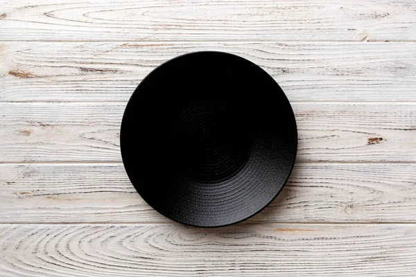 在木制背景上俯瞰着黑色的盘子 你的设计空间是空的 — 图库照片