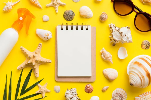 Blank writing book with summer beach accessories on background, copy space. Flat lay with copy space.