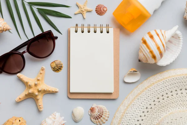 Blank writing book with summer beach accessories on background, copy space. Flat lay with copy space.