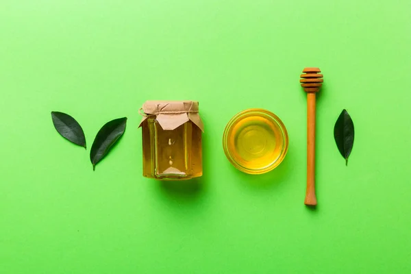 Honey jar with wooden honey dipper on white background top view with copy space. Delicious honey bottle.