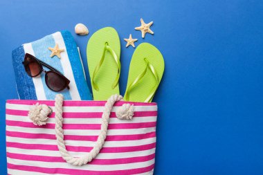 Plaj aksesuarları renkli arka plan yaz seyahati konseptinde düz bir görünüm sergiliyordu. İçinde deniz yıldızı ve deniz kabuğu olan bir çanta. Üst görünüm.