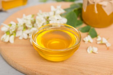 Tatlı bal kavanozu bahar akasyası çiçeklerini sarmıştı. Kavanozdaki kaşıktan bal akar. Tahta zemin üzerinde taze akasya balı kavanozları.