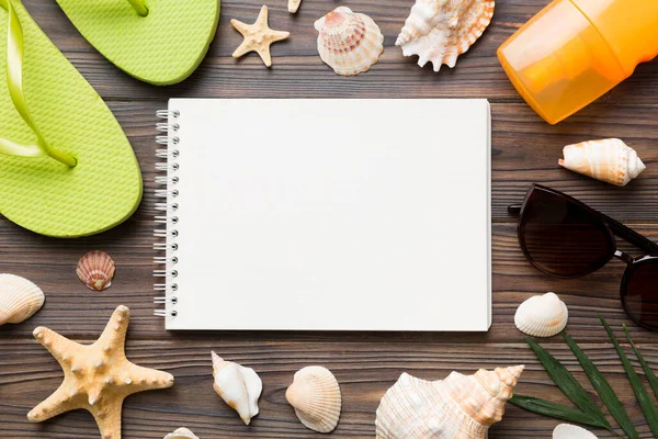 Blank writing book with summer beach accessories on background, copy space. Flat lay with copy space.