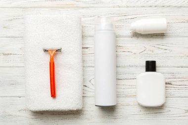 Tıraş Adam seti. Traş makinesi, havlu, losyon ve renkli arka planda tıraş köpüğü. Erkekler banyo aksesuarları üst görünüm.