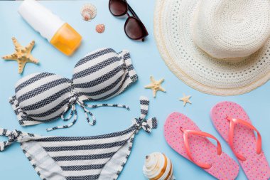 Kadın mayo ve plaj aksesuarları renkli arka plan yaz seyahati konseptine düz bir görünüm kazandırıyordu. Bikini mayo, hasır şapka ve deniz topuklu ayakkabı. Üst görünümü kopyala.
