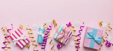 Renkli kağıda sarılı ve renkli arka planda konfetiyle süslenmiş hediye kutularıyla tatil dairesi yatıyordu. Noel, Doğum günü, Sevgililer Günü ve satış konsepti, üst manzara.