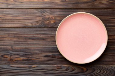 Ahşap arka planda boş pembe tabağın üst görüntüsü. Tasarımın için boş boşluk.