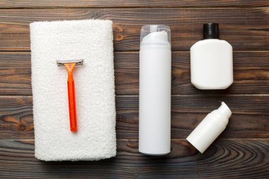 Tıraş Adam seti. Traş makinesi, havlu, losyon ve renkli arka planda tıraş köpüğü. Erkekler banyo aksesuarları üst görünüm.