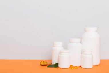 Omega-3 kapsülleri yeşil yapraklı arka planda beyaz bir şişede yatar. Balık yağı tabletleri. Biyolojik olarak aktif katkı maddeleri. Omega 6, Omega 9, A vitamini, E, D vitamini, D3 vitamini..