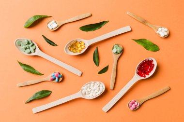 Renkli arka planda tahta kaşıkta vitamin ve mineral haplarının üst görünümü. Muhtelif ilaç haplarının en üst görüntüsü. Beslenme takviyesi sağlık ürünleri.
