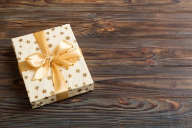 Noel 'i ya da diğer tatil hediyelerini renkli arka planda altın kurdeleli beyaz kağıda sardım. Şimdiki kutu, renkli tabloda hediye süslemesi, kopya alanı ile üst görünüm.