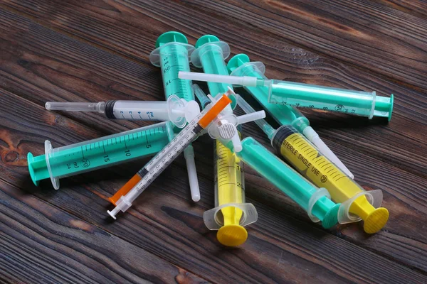 Top view of a pile of syringes and insulin syringes ready for injection at wooden background. Health care concept with copy space.