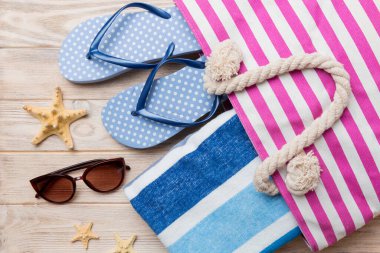 Plaj aksesuarları renkli arka plan yaz seyahati konseptinde düz bir görünüm sergiliyordu. İçinde deniz yıldızı ve deniz kabuğu olan bir çanta. Üst görünüm.