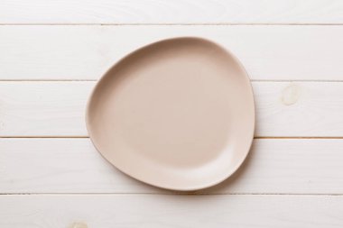 Ahşap arka planda boş pembe tabağın üst görüntüsü. Tasarımın için boş boşluk.