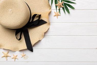 Summer holidays. Summer concept with straw hat and tropical leaf. Flat lay, top view, copy space.