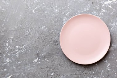 Çimento arka planındaki boş pembe tabağın üst görüntüsü. Tasarımın için boş boşluk.