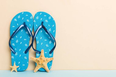 Plaj aksesuarları. Renkli arka planda parmak arası terlik ve denizyıldızı. Kopyalama alanı kullan.